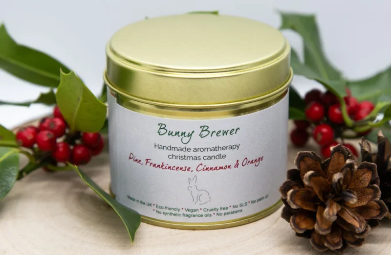 Handmade aromatherapy Christmas candle surrounded by holly